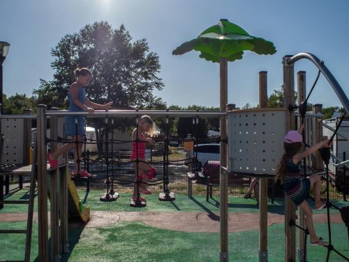 a man and two children playing on a playground at Camping Les Jardins de la Mer in Merlimont