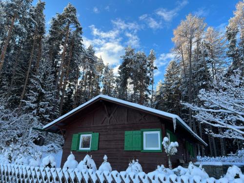 ein schneebedecktes Haus vor einem Zaun in der Unterkunft Waldchalet am Eichhof in Innsbruck