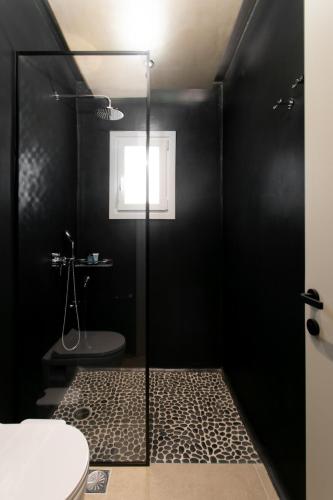 a black bathroom with a shower and a toilet at Eden Beachfront Residences & Suites in Kastraki Naxou