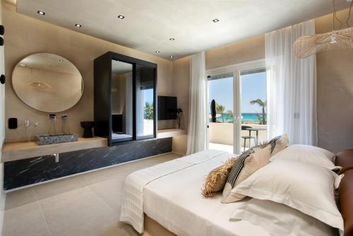 1 dormitorio con 1 cama grande y espejo en Eden Beachfront Residences & Suites en Kastraki