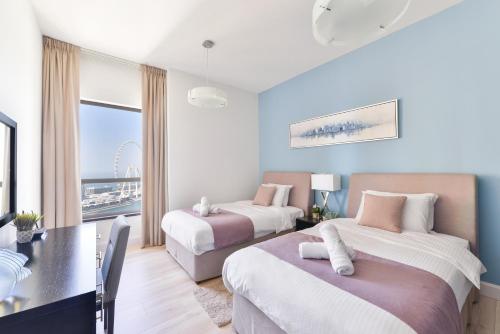 a hotel room with two beds and a table and a desk at Luxury JBR Shams · Full Sea View · Free 5* Beach Resorts Access! in Dubai
