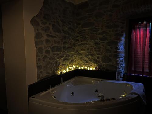 eine Badewanne mit Licht an einer Steinmauer in der Unterkunft Mansarda Pescia in Pescia