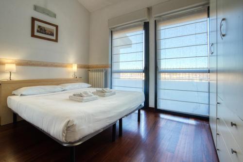 a bedroom with a bed with white sheets and windows at Italianflat - Il Giardino del naviglio Terrace in Milan