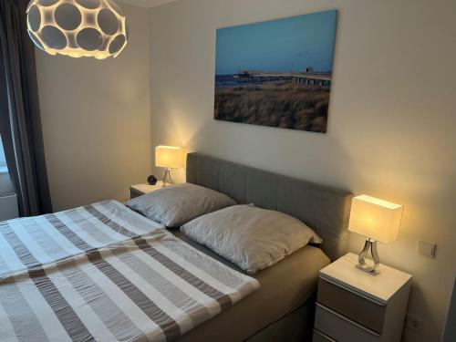 een slaapkamer met een bed met 2 lampen en een schilderij bij Heimathafen inkl Saisonstrandkorb und Waschmaschine in Heiligenhafen