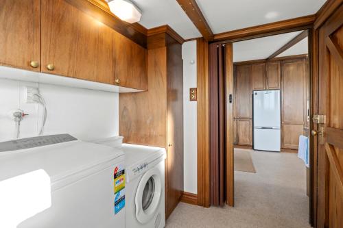 uma cozinha com uma máquina de lavar roupa e um frigorífico em The Professor's Beach House - Brighton Home em Mosgiel
