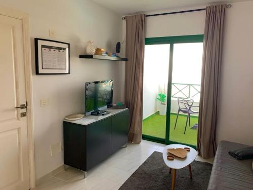 een woonkamer met een tv en een groot raam bij Coqueto apartamento ZUA con piscina in Costa Teguise