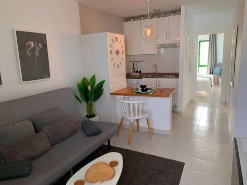 een woonkamer en een keuken met een bank en een tafel bij Coqueto apartamento ZUA con piscina in Costa Teguise
