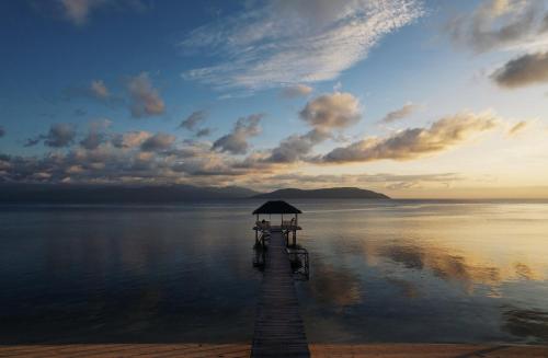 Ampana的住宿－Reconnect - Private Island Resort & Dive Center Togean - Buka Buka Island，日落时分在水面上带雨伞的码头