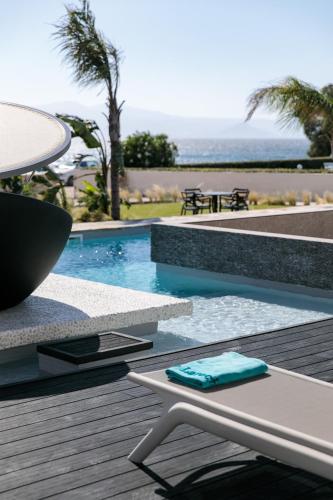 a swimming pool with a table and a table at Eden Beachfront Residences & Suites in Kastraki Naxou