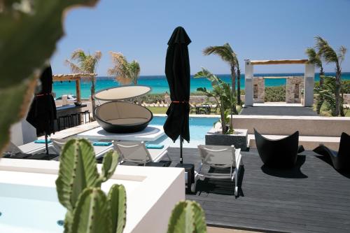 a resort with a pool and chairs and a table at Eden Beachfront Residences & Suites in Kastraki Naxou