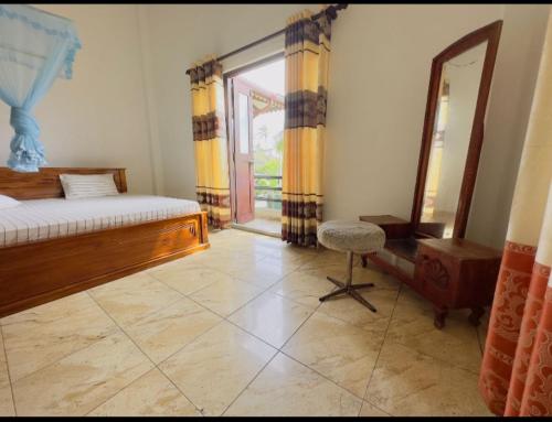 a bedroom with a bed and a mirror and a chair at Royal beach villa in Unawatuna