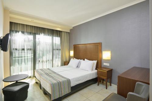 a hotel room with a bed and a window at Mediterranean Resort in Paralia Katerinis