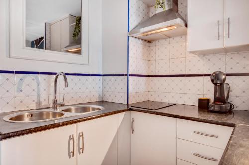 Elle comprend une petite cuisine avec des placards blancs et un évier. dans l'établissement Precioso apartamento en La Nogalera - Vista al mar, à Torremolinos