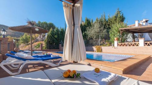 a pool with a table and chairs and an umbrella at Mirador Las Claras Iznate by Ruralidays in Iznate