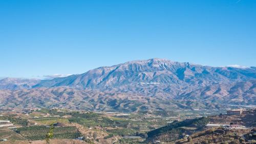 a view of a mountain with trees and a city at Mirador Las Claras Iznate by Ruralidays in Iznate