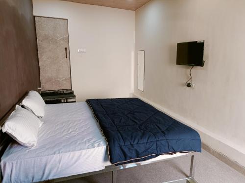 HOTEL ROYAL INN في Satna: غرفة نوم مع سرير وتلفزيون على الحائط
