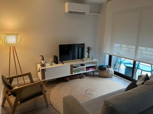 - un salon avec une télévision et un canapé dans l'établissement Foz Relógio Apartment, à Figueira da Foz