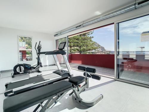 - une salle de sport avec un tapis de course et une grande fenêtre dans l'établissement 2br apartment with parking near Monaco, à Beausoleil