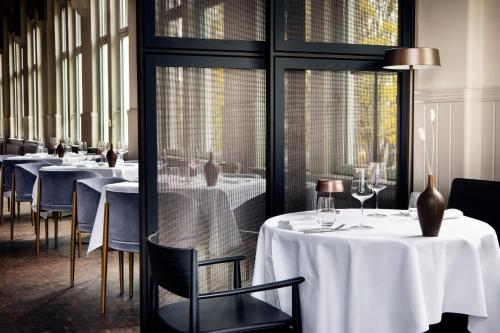 a restaurant with white tables and chairs and windows at Pillows Grand Boutique Hotel Maurits at the Park - Small Luxury Hotels in Amsterdam