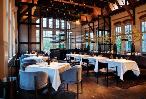 a restaurant with white tables and chairs and windows at Pillows Grand Boutique Hotel Maurits at the Park - Small Luxury Hotels in Amsterdam