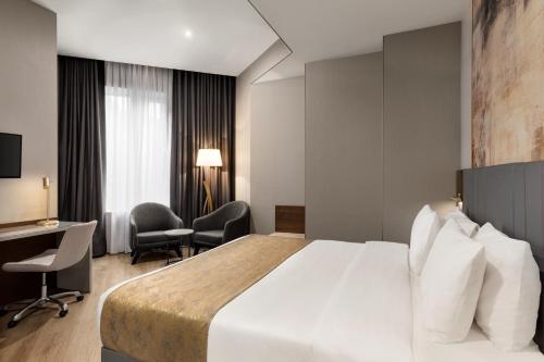 a hotel room with a bed and a desk at Tbilisi Chambers, Trademark Collection by Wyndham in Tbilisi City