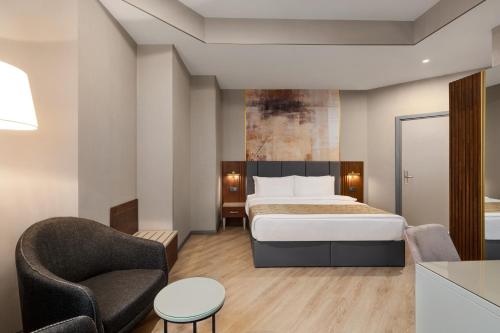 a hotel room with a bed and a chair at Tbilisi Chambers, Trademark Collection by Wyndham in Tbilisi City