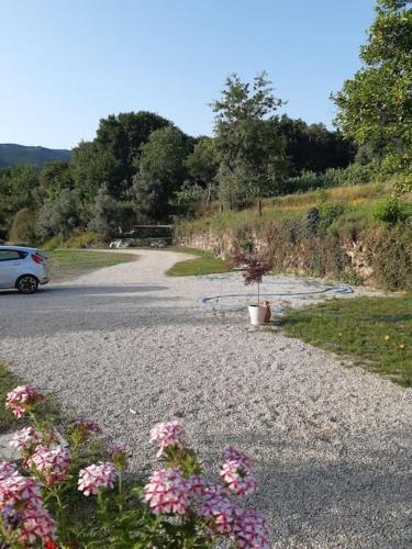 a gravel road with a car and flowers on it at A CASA COM 2 PEREIRAS in Terras de Bouro