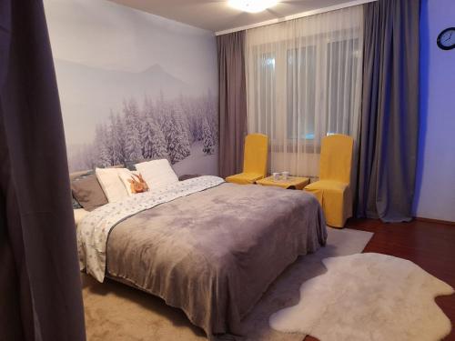a bedroom with a bed and two yellow chairs at Sibirska Central in Kolašin