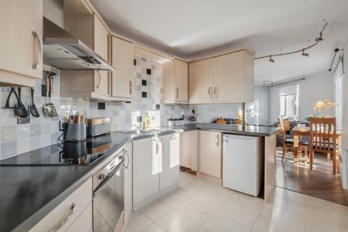 a kitchen with white cabinets and black counter tops at Cosy countryside apartment in Wellingborough