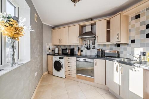 a kitchen with wooden cabinets and a washer and dryer at Cosy countryside apartment in Wellingborough