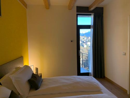 a bedroom with a bed and a large window at Guest House Le Cassandre in Sondrio