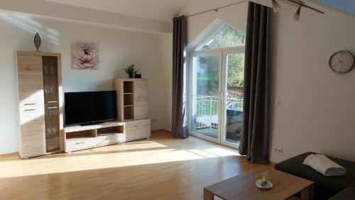 a living room with a tv and a sliding glass door at Ferienwohnung Tina in Breitenberg