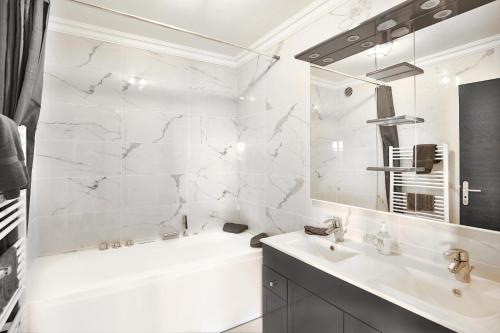 uma casa de banho branca com uma banheira e um lavatório em Magnifique 4 pièces avec Terrasse, Piscine em Mandelieu-la-Napoule
