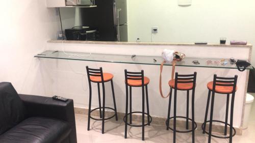 a counter with four bar stools in a room at Angra inn Ap quarto e sala (temporadas) in Angra dos Reis