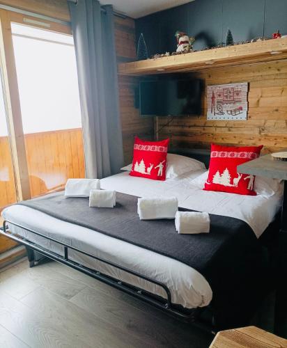 une chambre avec un grand lit avec des oreillers rouges dans l'établissement Chalet Olympie, Appartement avec balcon et vue montagne, ski aux pieds, Méribel-Mottaret, à Méribel
