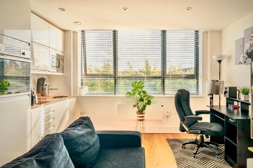 ein Wohnzimmer mit einem Sofa, einem Schreibtisch und Fenstern in der Unterkunft Comfort Stay Apartment - Haywards Heath in Haywards Heath