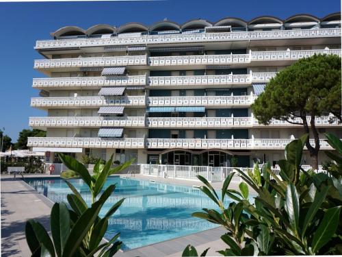 un gran edificio con una piscina frente a él en Amazing studio with pool and terrace en Porto Santa Margherita di Caorle