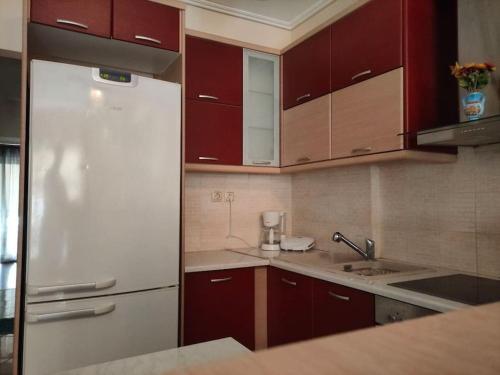 eine Küche mit roten Schränken und einem weißen Kühlschrank in der Unterkunft Το σπίτι της Περσεφόνης in Athen