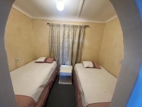 two beds in a small room with a window at The Beach Shack Glamping & The Boat Shed in St Helena Bay