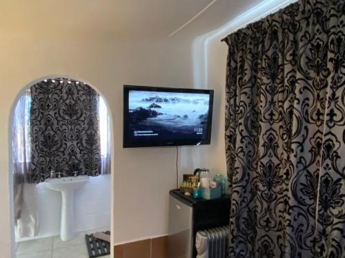 a bathroom with a tv on the wall and a curtain at The Beach Shack Glamping & The Boat Shed in St Helena Bay
