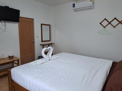 a bedroom with a white bed with swans on it at เรือนจำปา ( Rueanjumpa resort ) in Ban Na Kai