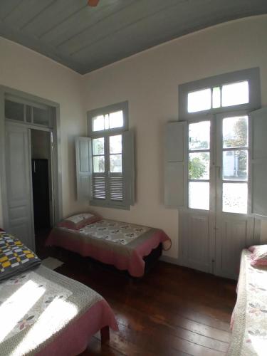 a room with two beds and two windows at Pousada Gameleira in Diamantina
