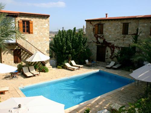 a swimming pool in front of a house with umbrellas at Porfyrios Country House in Chirokitia