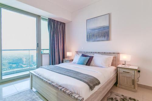 a bedroom with a bed and a large window at Scenic High Floor 1BR at Ocean Heights, Dubai Marina by Maxx Value Homes in Dubai