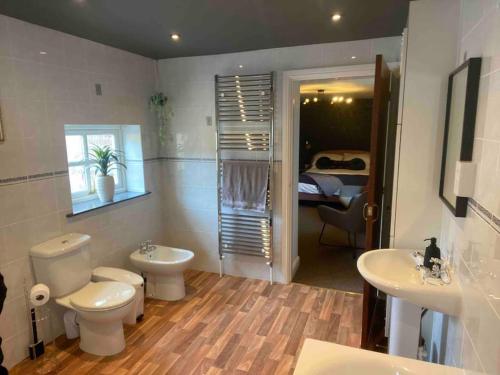 a bathroom with a toilet and two sinks and a bedroom at The Shires - Quirky 3 bed holiday home with Wood-fired Hot-tub in Rudston