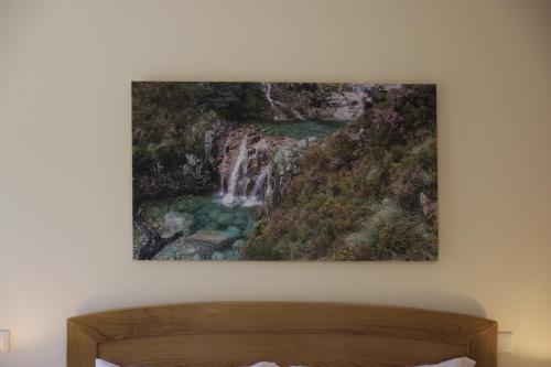 a painting of a waterfall on a wall above a bed at Casa da Fonte - Gerês in Geres