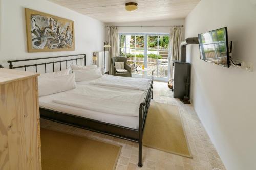 齊諾維茨的住宿－Usedom Refugium，一间卧室配有一张带白色床单的床和电视。