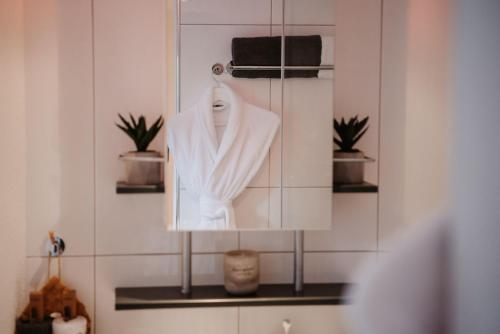 a white robe hanging on a rack in a bathroom at Sunny Way Home Accommodation & Spa in Weite