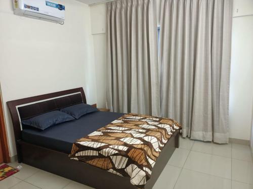 een slaapkamer met een bed en een raam met gordijnen bij Royal Nest 3 Rooms appt in Pune