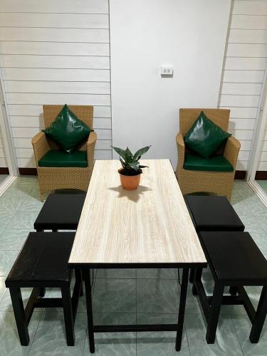 uma mesa de madeira com duas cadeiras e um vaso de plantas em บ้านพักสำหรับ 10 ท่าน em Udon Thani